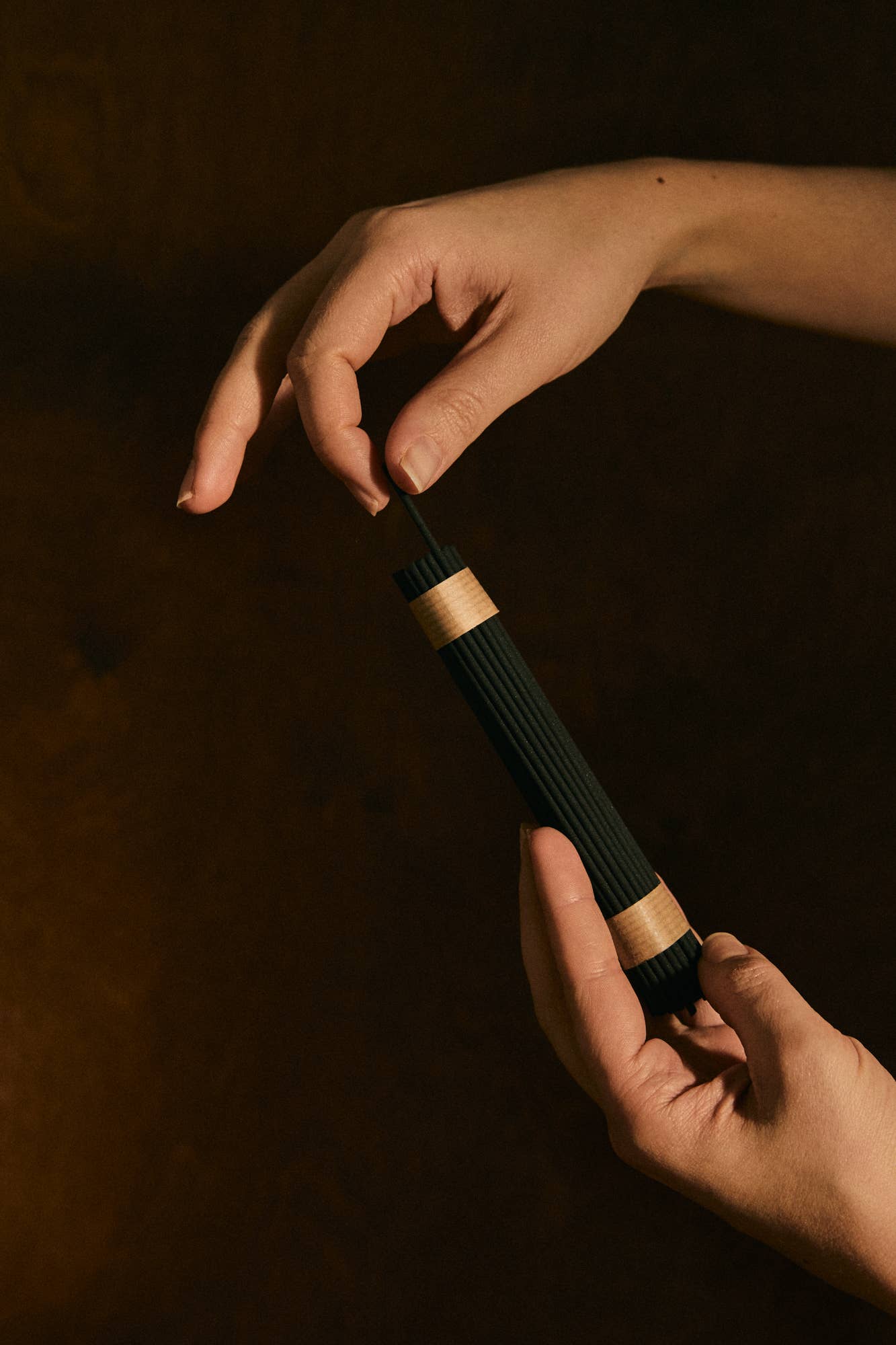 Two hands holding a black and gold object against a dark background
