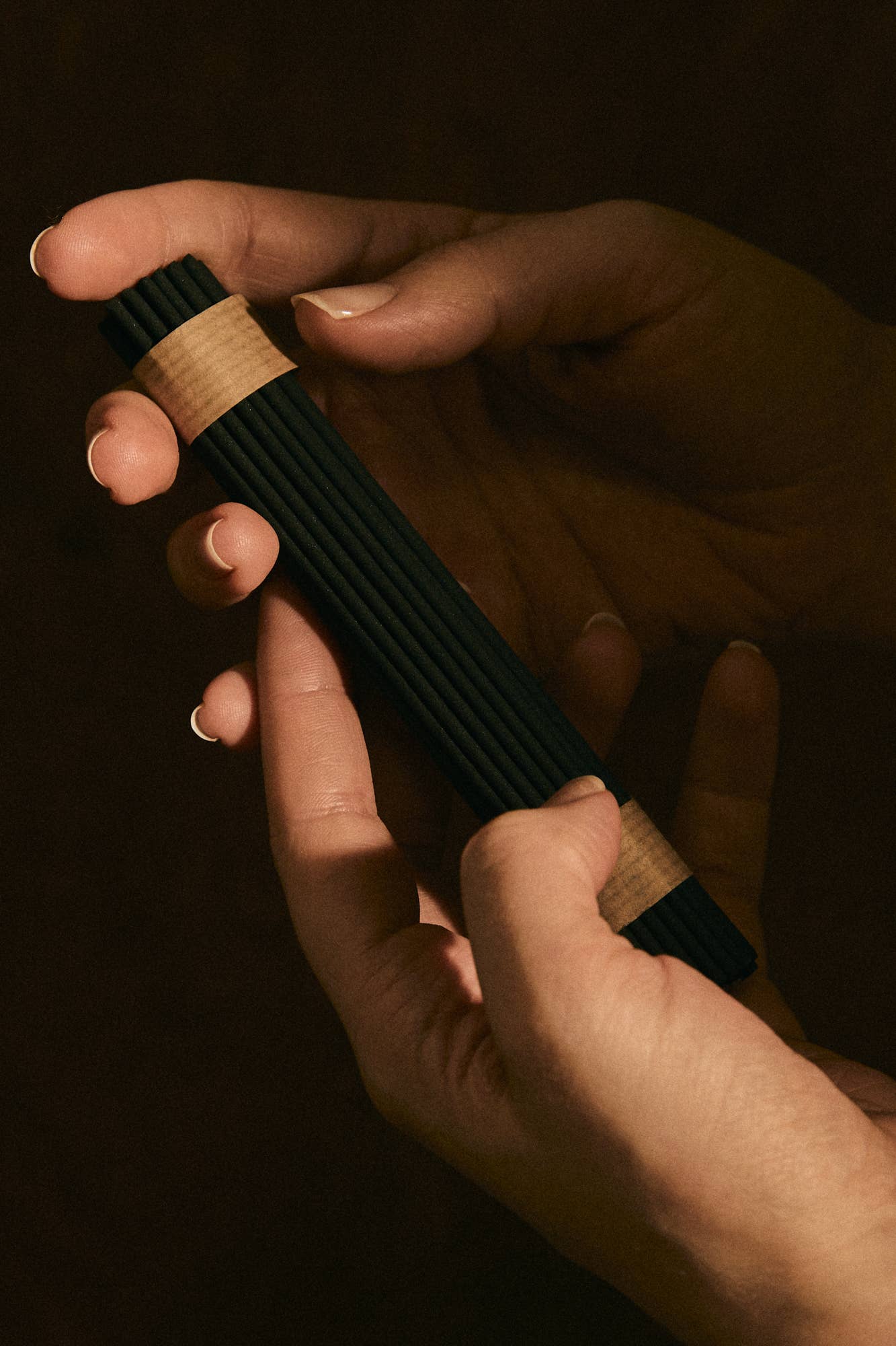 Hand holding a black and wooden object against a dark background