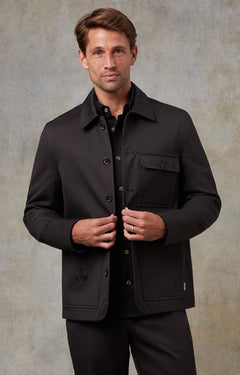 Man wearing a black jacket against a neutral background