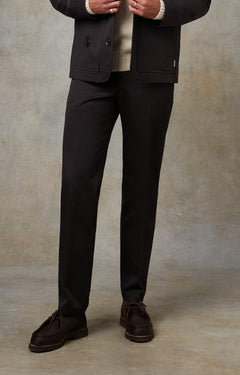 Person wearing a dark suit with a beige shirt against a neutral background