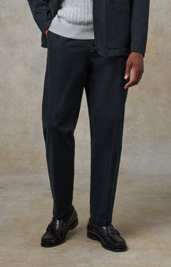 Person wearing black pants and dark shoes against a beige background