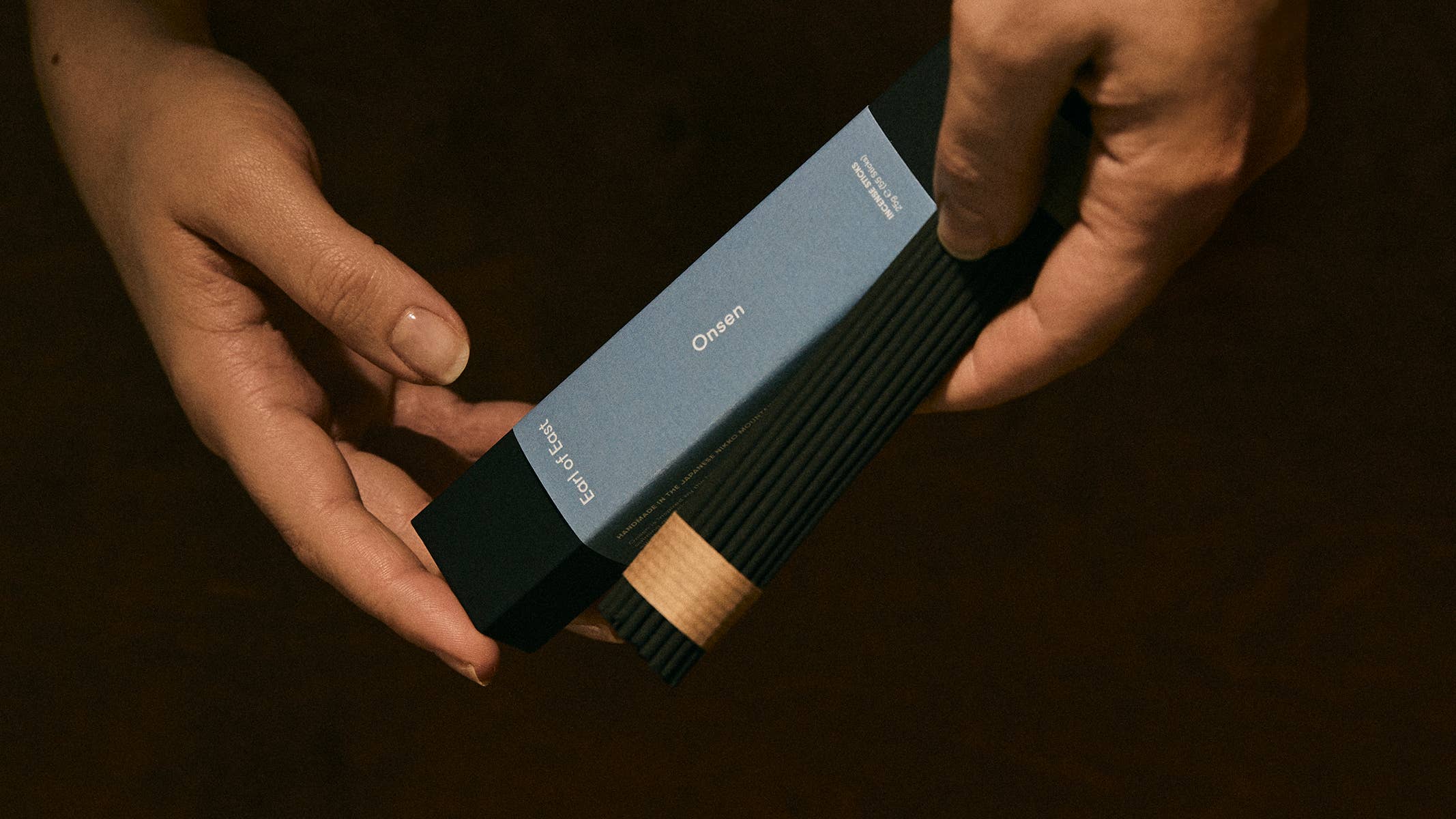 Person holding a cylindrical electronic device with a dark background