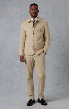 Man wearing a beige suit standing against a plain background