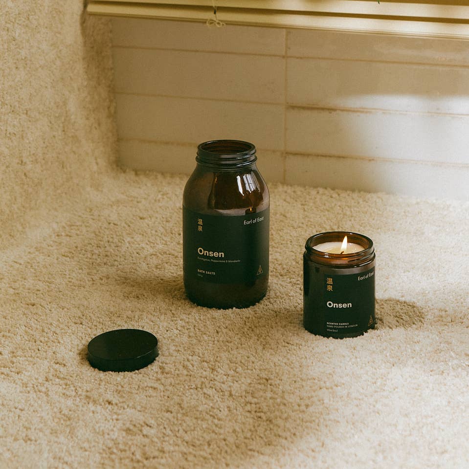 Onsen candle and jar on a textured surface with tiled wall background