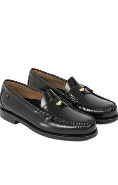 A pair of black leather penny loafers with gold-tone metal studs and a low stacked heel, shown on a plain white background.